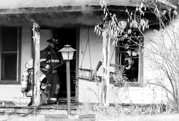 Chandler firefighters hose down flames, visible through the window on the right, at a house at 116 East 1st Street Tuesday morning. No injuries were reported. Photo/Brian Blansett