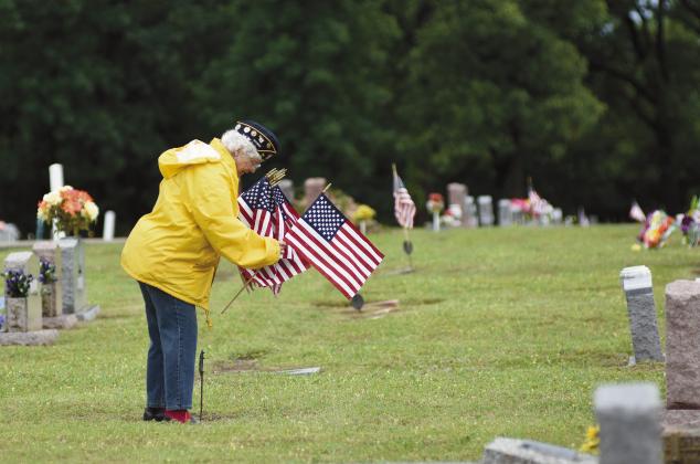 Eileen VanSteenwyk from Agra places flags on the graves of veterans at Oak Park Cemetery in Chandler on Saturday. Photo/Brian Blansett.