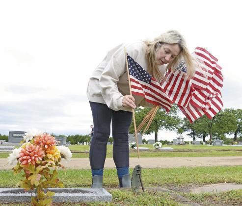 Ashley Weaver from Chandler places flags on veterans’ graves on Saturday. Photo/Brian Blansett.
