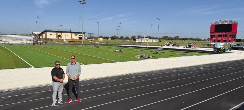 North Rock Creek athletic director Evan Smith, left, and superintendent Blake Moody stand by the new turf going in on the Cougars’ home field. It was get its baptism by fire this Friday when NRC hosts Holdenville. Photo/Brian Blansett