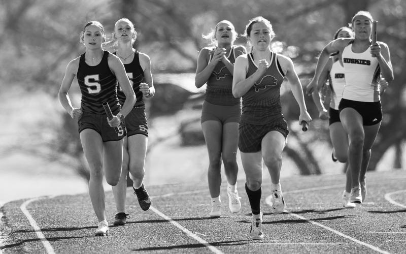 Olivia Stanger from Stroud (left) and Adelaide Furtado from Chandler take off after the first exchange in the girls 4x100 relay Saturday at Stroud. Looking on after handing off the sticks are Lacy Williams from Stroud and Skye Buchanan from Chandler. Photo/Beth Young