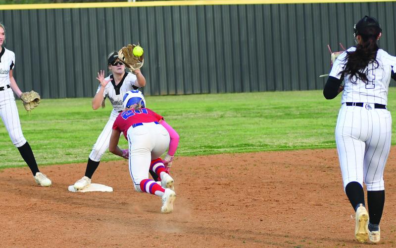 Chandler’s Ruthie Capps (20) dives back to second as Meeker’s Ryean Weaver takes the throw following a rundown in the Lady Lions’