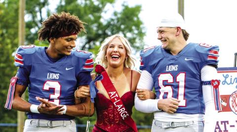 At-Large candidate Lizzy Kliewer grins as her named is called for Homecoming queen in Chandler on Friday night. Her escorts are Darius Wade (left) and Boston Christy (right). Photo/Jennifer Pryor