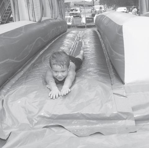 This slide tunnel was one of two water inflatables set up at the Unity in the Community event held at Tilghman Park in Chandler. Here, Chandler second grader Noah, 9 years of age, shows others how to get wet while having fun.