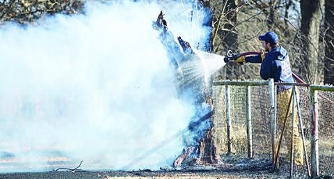 A firefighter hoses down a backyard tree that had caught on fire.