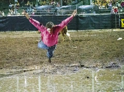 McLoud steer wrestler Dally Trussell from McLoud threw his steer Tuesday night at the International Finals Youth Rodeo and celebrated with a dive into a large pool of rainwater that collected in the area after an early evening shower. Dally emerged muddy but happy and qualified for the short go-round, and finished seventh in the average on three steers. Photo/Brian Blansett