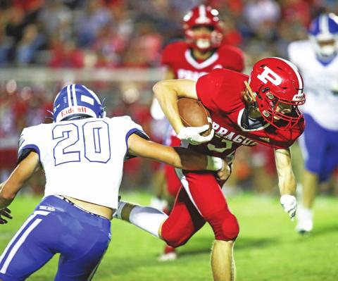 Aiden Auld rushes for Prague during the Red Devils’ homecoming win Friday night while Stroud’s Bryce Hughey (20) tries to slow him down. Photo/Rick Hester