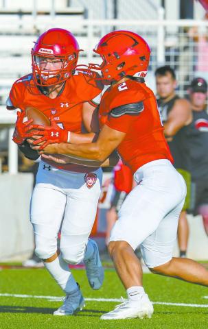 Senior quarterback NolanYates (2) hands off the ball to Cruz Shiltz (7) on the read option duringg Prague’s scrimmage with Harrah. Photo/Rick Hester
