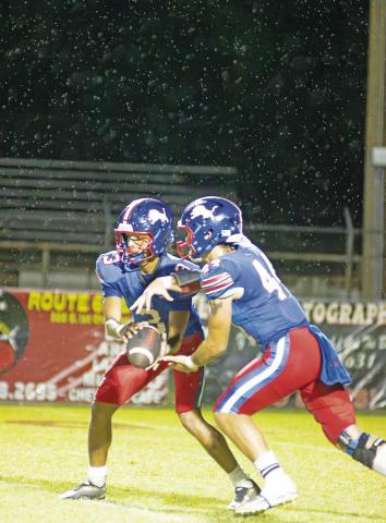 Chandler quarterback Darius Wade hands off to Roanon Wolford underneath a dripping sky Friday night at Joe Telford Field. The Lions beat Casady, 41-6, during a game that was played under a continual light rain. Now 3-1 in district, Chandler is tied with Lindsay for second place and will host the Leopards at 7 p.m. Friday. The winner will have the pole position for getting a home game for the first round of the playoffs. Photo/Brian Blansett