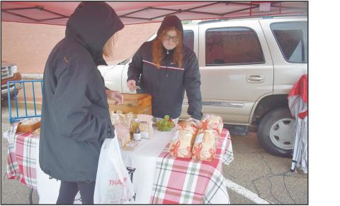 Paige Coyle (right) from Coyle Family Farms helps a customer pick out a loaf of sourdough bread at her stall on April 5. It was the opening day of the season for the 2A Chandler OK Farmers Market. Photo/Emily Kalka