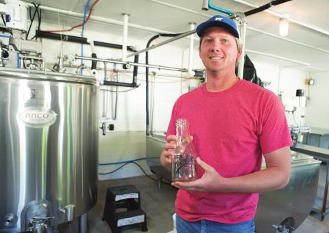 Travis Marak holds one of the milk bottles in the dairy in Meeker. Photo/Brian Blansett