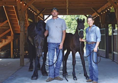McLoud couple Cory (left) and Melody (right) Martin stand inside their stable with their two Fresians, Lady Lorelei (left) and her daughter, Aurora Avail (left). The two built the stable themselves with help from friends and family. Melody is passionate about sharing her love for Fresian horses, as well as the many causes she champions and supports, such as Cargo Ranch and Guardians of the Forest. Photo/Emily Kalka