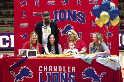 Chandler senior Chloe Hyde (second from left in front) signs on to cheer at the University of Oklahoma in Edmond at Freeman Fieldhouse on April 28. Seated to her left is Hannah Smith with CHS Cheer Coach Cynthia Snyder on her right holding Hyde’s little sister Katie. On the end is Anna Long, Hyde’s mother. Standing behind them is Hyde’s father JC Hyde. Photo/Emily Kalka