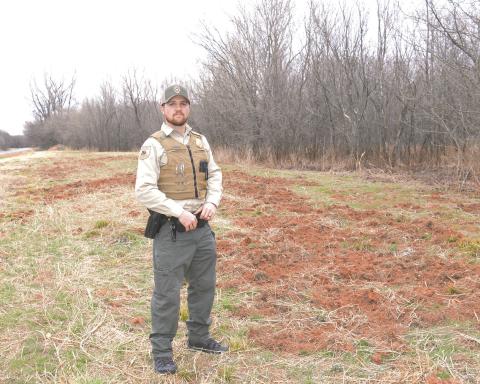 Game Warden Jacob Harriet stands along Highway 18, where wild hogs have rooted up the right of way in search of food in January. Photo/Brian Blansett