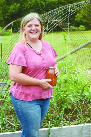 Lisa Smith stands in her back garden while holding one of her home produced jars of salsa. Photo/Bradley Jager