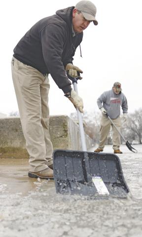 Rodney Barnett, foreground, and Virgil Wilson break ice off the sidewalk at the Lincoln County Courthouse Monday morning following the storm that came through Sunday evening. The second winter storm in a week, it closed schools and offices and the roads in Lincoln and Pott County were slick and dangerous. Photo/Brian Blansett