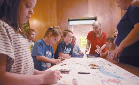 Kids color at Stroud Public Library’s summer reading program on June 4. Left to right: Khloe Whitson, Raymond Richardson (standing in background), Annie Richardson, Lewis Richardson, Evan Grammer, Marsha Morgan, Suzanne Richardson, and Stacy Parsons. Photo/Emily Kalka