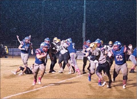 Above, Dylan McKinney runs through the rain for a fourth-quarter touchdown against Okemah.