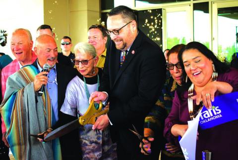 Iowa Tribe of Oklahoma Chairman Jacob Keyes (center) cuts the ribbon at the new Harrah’s Oklahoma casino alongside members of the tribe’s business committee and SVP/GM Joe Scibetta (second from left). In the background are Oklahoma legends Barry Switzer and Bob Stoops, who were special guests for the grand opening on April 9. Photo/Emily Kalka