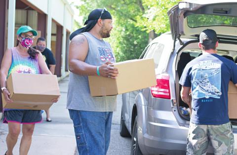 Volunteers Donna Price, Kevin Fields and Kyle Robertson load food boxes into the back seat of a vehicle. Photo/Chelsea Weeks